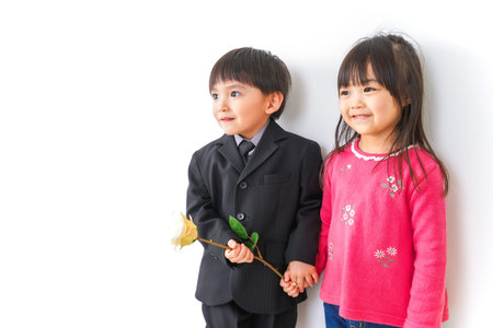 Children in uniforms and a flower in front of a white wall