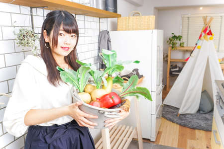 young woman holding vegetablesの写真素材