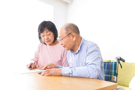 Elderly couple sitting at the table and writing on paper.の写真素材