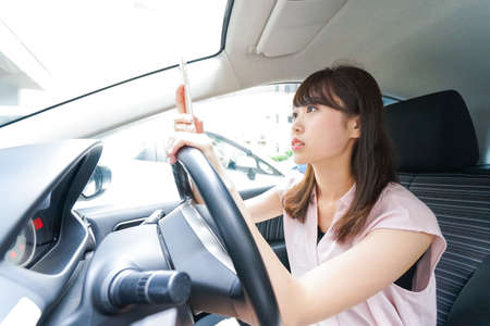 Driving woman using smartphoneの写真素材