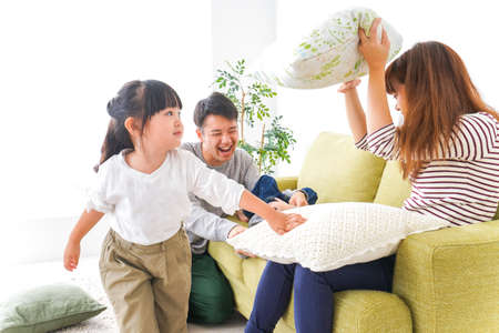 Happy family playing pillow fight in living room at home high quality photoの写真素材
