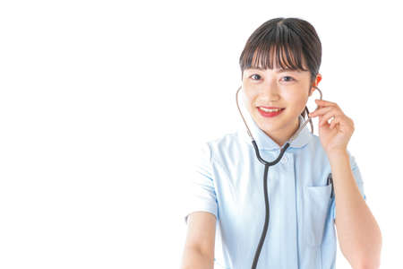 Nurse listening to a stethoscope shot in the studio.の写真素材