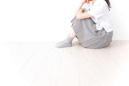 Young woman sitting on the floor and suffering from back pain. Health care concept.の写真素材