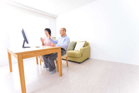 Mature couple sitting at the desk in the living room and talkingの写真素材