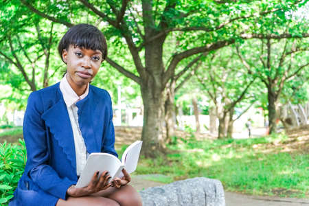 african woman reading a book at parkの写真素材