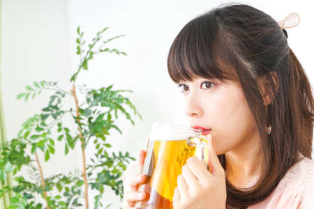 Young woman drinking beer at homeの写真素材