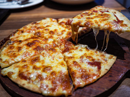 Pizza garnished with cheese on a wooden board.