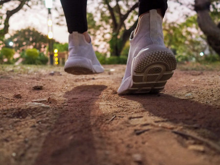 Runners move forward with white shoes on the ground in the park.