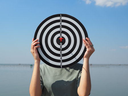 girl holding a dart board hiding face Business goals, goals that lead to success strategic planning ideasの写真素材