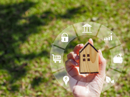 Young woman's hand holding a wooden house. Showing a model. Digital. Genius. Smart house technology, innovation of the future.の写真素材