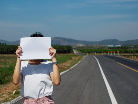 Young Asian woman holding a front page. On the street. Billboard. White space for your copy.の写真素材