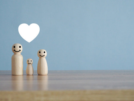 Wooden puppet family on wooden table with white heart iconの写真素材