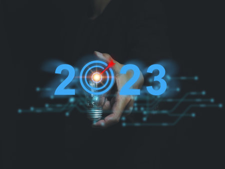 Businessman holding a lightbulb with a red goal in the middle on 2023. Start a new idea, a new project, a plan to deal with. Problems to achieve goals in the new yearの写真素材
