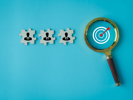 A person on a jigsaw puzzle searching for a target on a magnifying glass. Working as a team to...