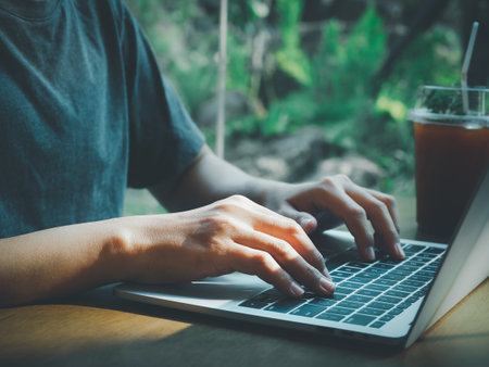 Man typing documents or searching on laptop with nature background. Light shines through.の写真素材