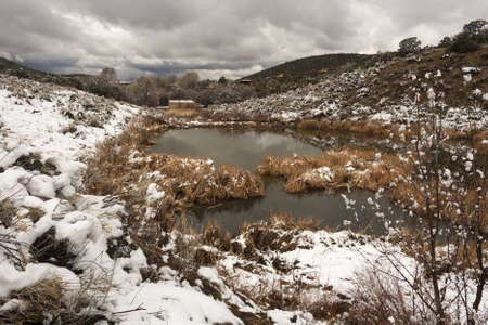 Landscape picture of a reservoir in the desert with snow and cloudsの写真素材
