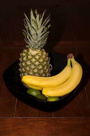 A vertical shot of a fruit bowl on dark wooden tableの写真素材