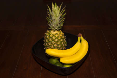 A horizontal shot of a fruit bowl on dark wooden tableの写真素材