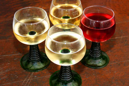 Four rustic wine glasses three with white one with red wineの写真素材