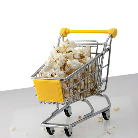A shopping cart filled with popcorn and some popcorns on the floorの写真素材
