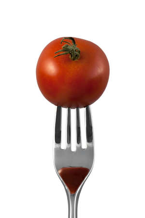 A whole tomato on a fork over white background with a reflection on the forkの写真素材