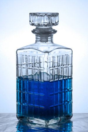 A crystal carafe filled with blue liquid in blue lightの写真素材