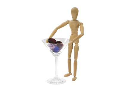 A wooden female doll is standing next to a cocktail glassの写真素材