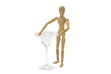 A wooden female doll is standing next to a cocktail glassの写真素材