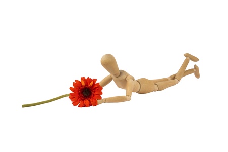 A wooden female doll is lying holding a flowerの写真素材