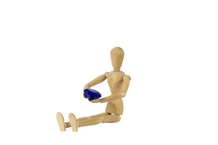 A wooden female doll is sitting and holding a diamondの写真素材