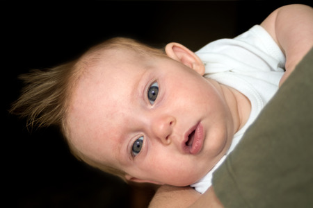 An almost four month old baby looking neutral on black の写真素材