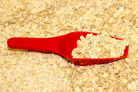 A red plastic scoop in an oceans of oatsの写真素材