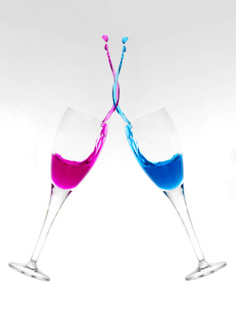 Two champagne glasses clinking and mixing liquidsの写真素材