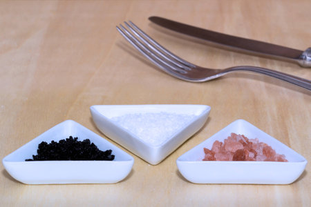 Three types of salt with silverware in backgroundの写真素材
