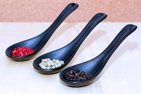 Three types of peppercorns on black spoonsの写真素材