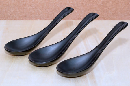 Three ceramic black spoons on a tableの写真素材