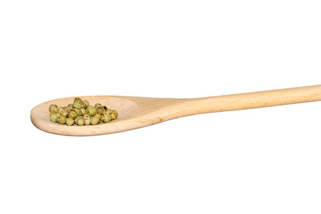 Green peppercorns on a wooden spoon isolated on whiteの写真素材