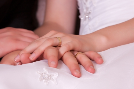 Photo crossed hands of newlyweds with wedding ringsの写真素材