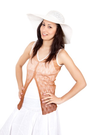 Brunette woman in white sun hat in a white dress, on white background, posing with hands on hipsの写真素材
