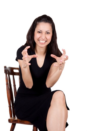 A woman in a black dress on a chair makes grimaces, isolated on white backgroundの写真素材