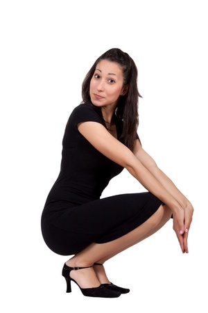 Brunette woman in black dress is squatting and doing a grimace, isolated on white backgroundの写真素材