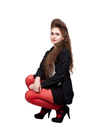 Teenage girl in black and red dress squatting and smiles, isolated on white backgroundの写真素材