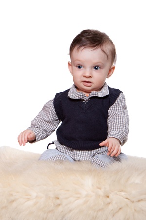 Little baby boy sitting on woolen fleece on a white backgroundの写真素材