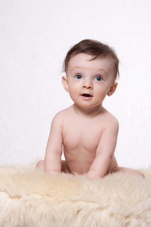 Little baby boy sitting on woolen fleece on a white backgroundの写真素材