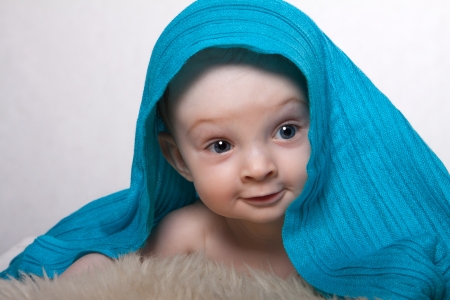 Little baby boy lying on woolen fleece on his head is blue blanket in a white backgroundの写真素材