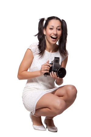 Retro woman in white dress, is squatting, holding the camera and laughs, isolated on white backgroundの写真素材