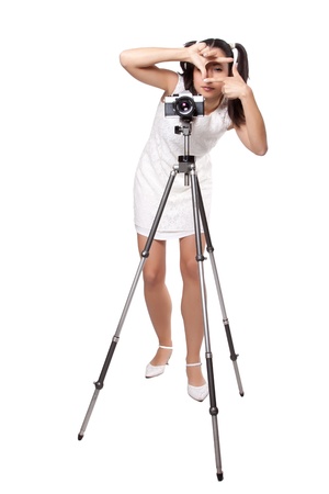 Retro woman in white dress, with an old camera on a tripod, creates a frame with her hands, isolated on white backgroundの写真素材
