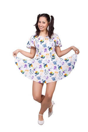 A girl with pigtails in colorful retro dress, a bending forward, stretched skirt, isolated on white backgroundの写真素材