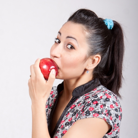 A woman is biting a red appleの写真素材
