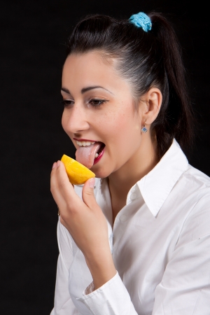 Woman holding in hands yellow lemon and licking itの写真素材